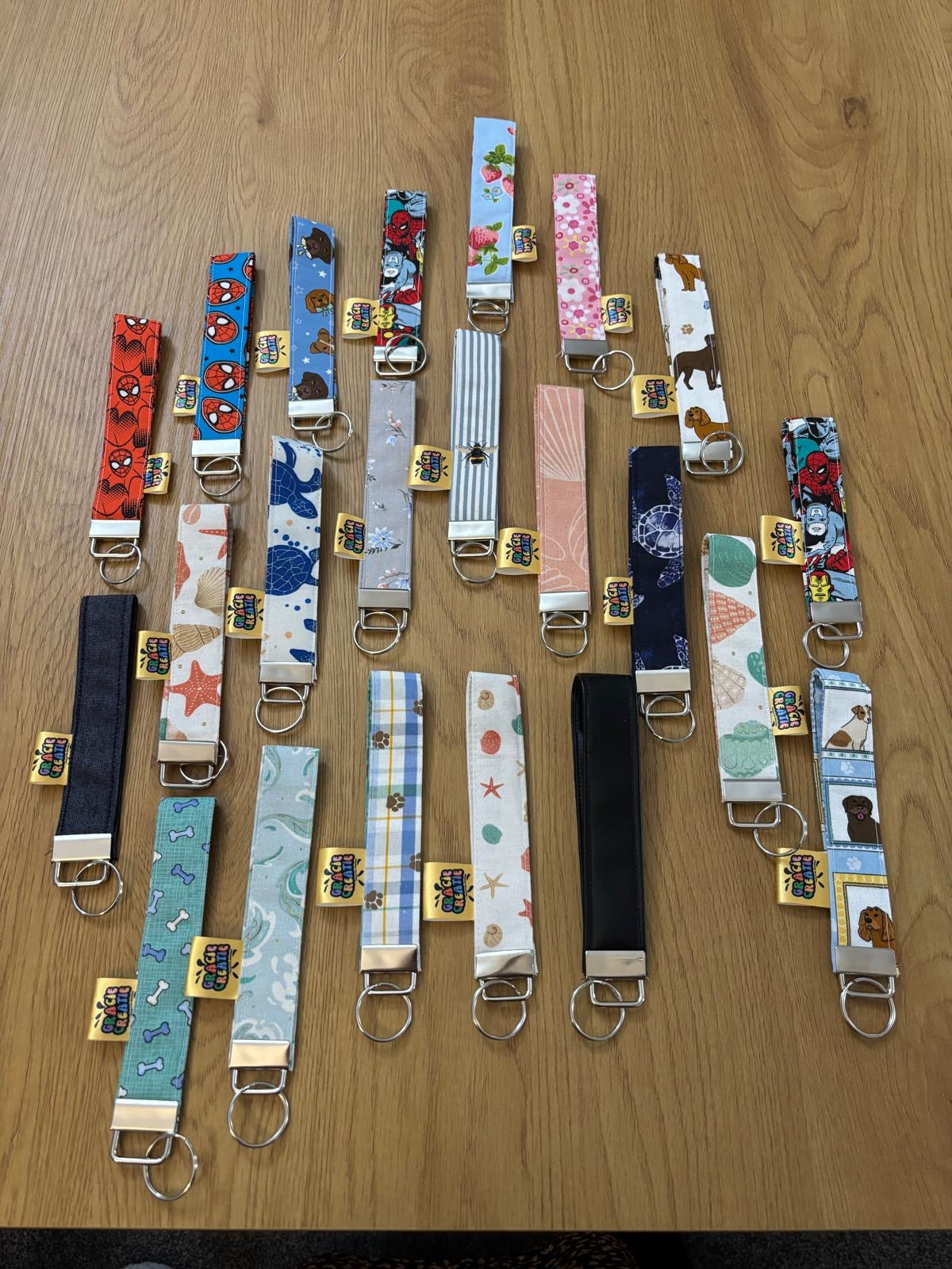 Collection of various patterned keyrings on a wooden surface. All with metal hardware.