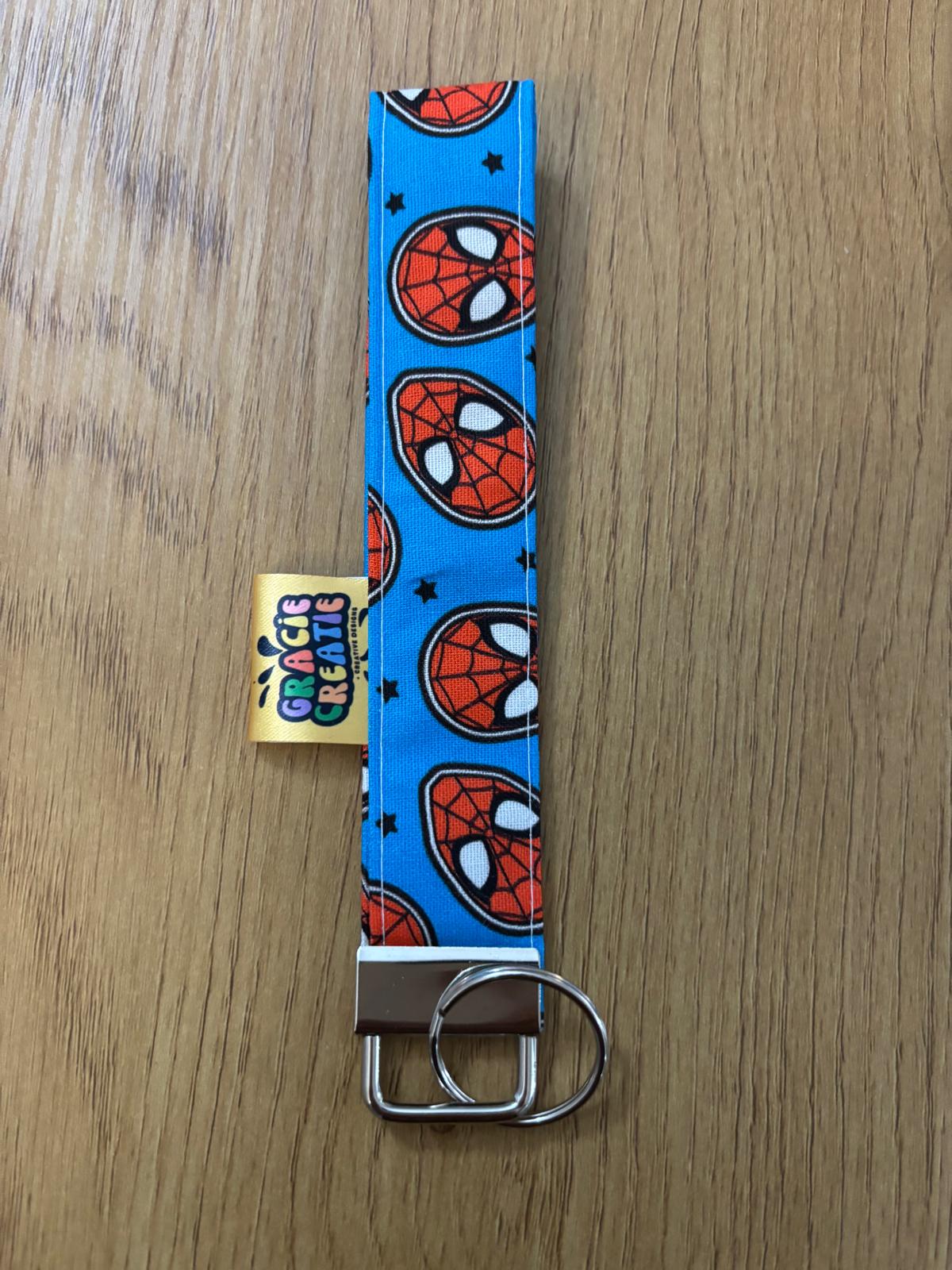 Spider-Man patterned keychain on a wooden surface with metal hardware