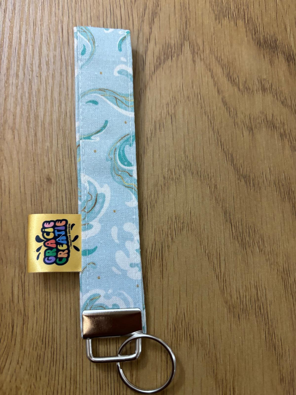Keychain with blue patterned strap with metal hardware on wooden surface