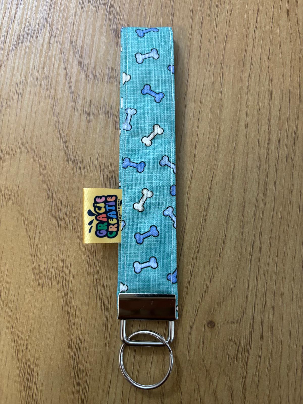Blue fabric keychain with bone pattern on a wooden surface with metal hardware