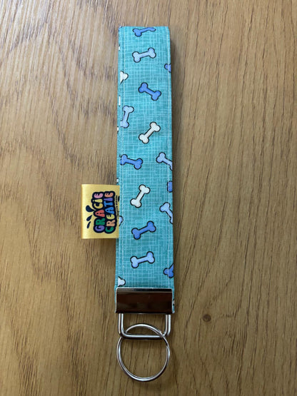 Blue fabric keychain with bone pattern on a wooden surface with metal hardware