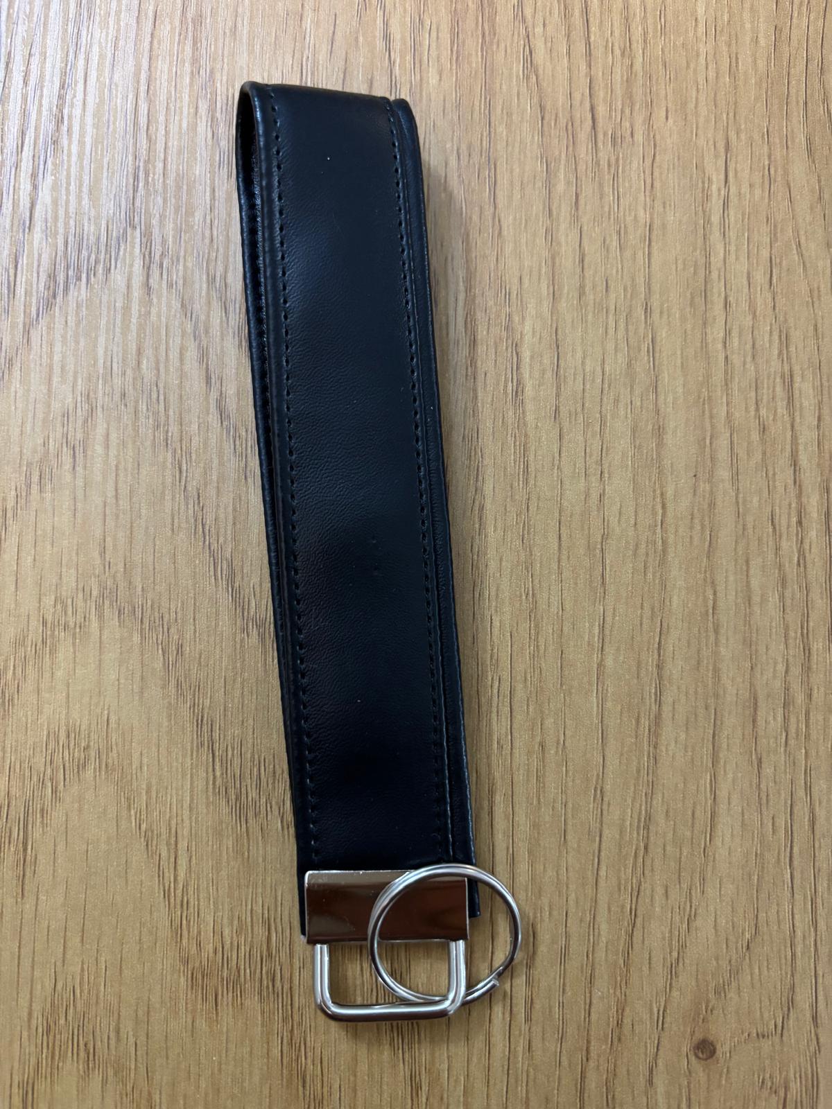 Faux Black leather belt with metal hardware on a wooden surface