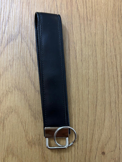 Faux Black leather belt with metal hardware on a wooden surface