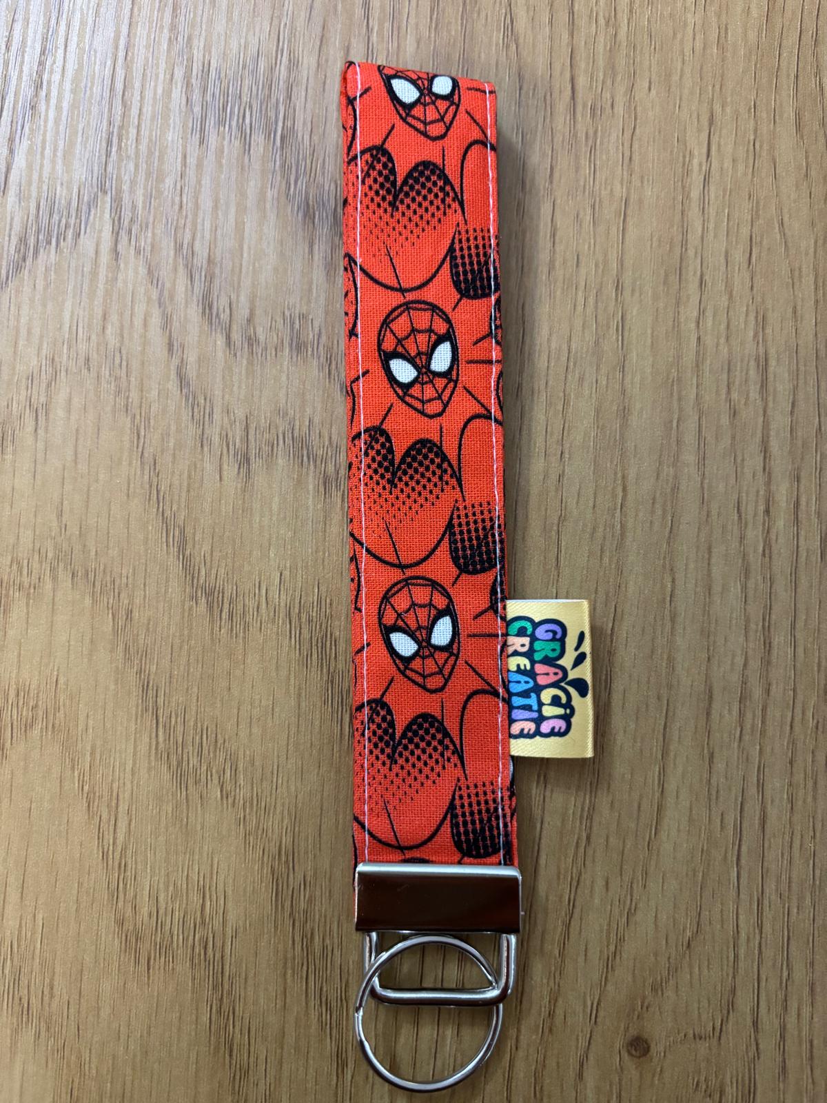 Keychain with Spider-Man pattern on a wooden surface with metal hardware