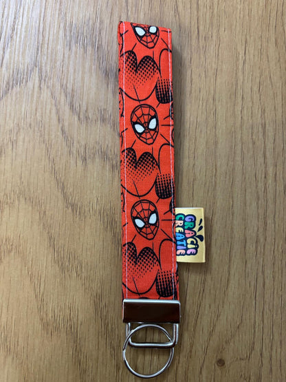 Keychain with Spider-Man pattern on a wooden surface with metal hardware