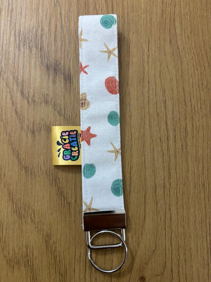 Keychain with starfish and shell pattern on a wooden surface with metal hardware