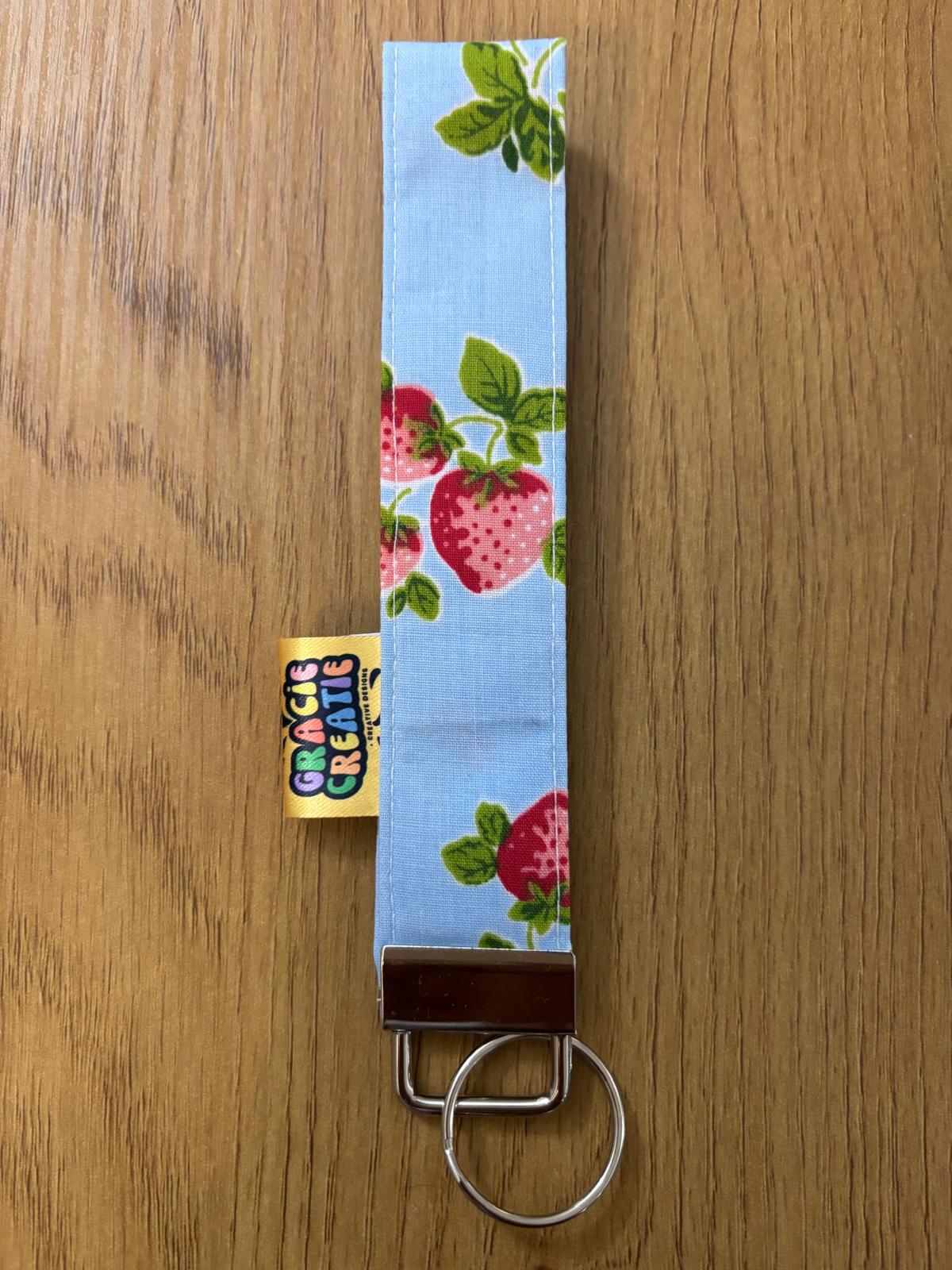 Keychain with strawberry design on a wooden surface with metal hardware
