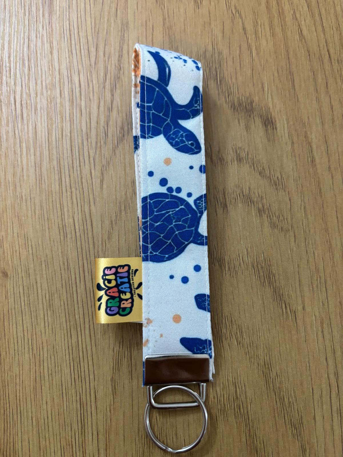 Keychain with blue turtle pattern on a white background on a wooden surface with metal hardware